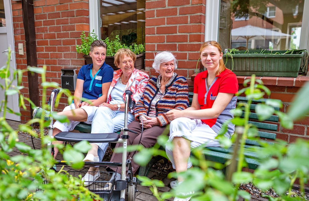 Fröhliche Pflegekranft zusammen mit lachenden Senioren